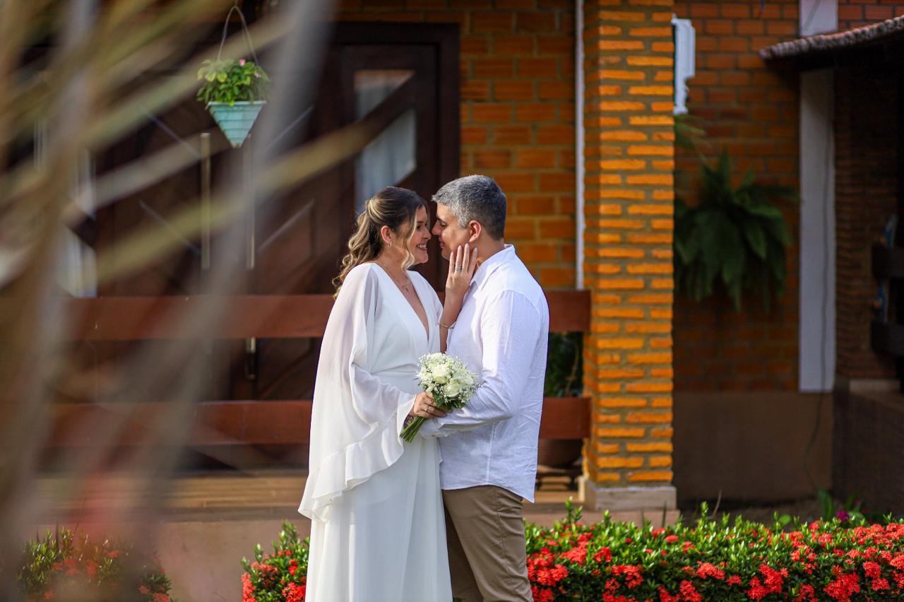 Samara e Francisco juntos diante de uma porta de tijolos